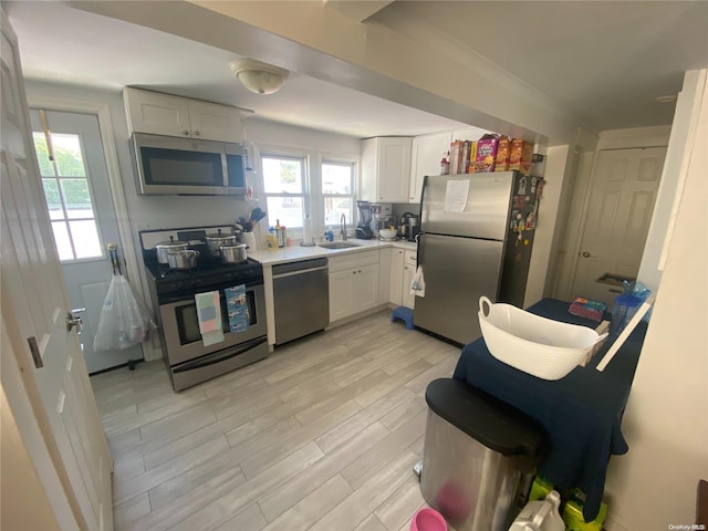 kitchen with white cabinets, light hardwood / wood-style floors, sink, and appliances with stainless steel finishes