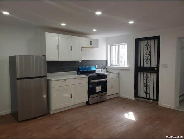 kitchen with white cabinetry, sink, stainless steel appliances, backsplash, and wood-type flooring