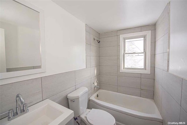 full bathroom with toilet, sink, tile walls, and tiled shower / bath combo