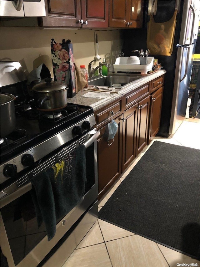 kitchen featuring double oven range, light tile patterned floors, sink, and dark brown cabinetry