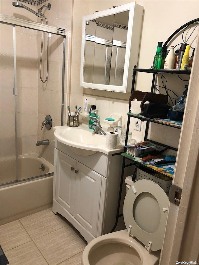 full bathroom featuring combined bath / shower with glass door, vanity, and toilet