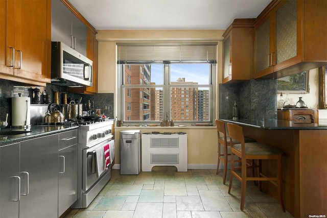 kitchen featuring tasteful backsplash, dark stone countertops, a breakfast bar, and stainless steel appliances