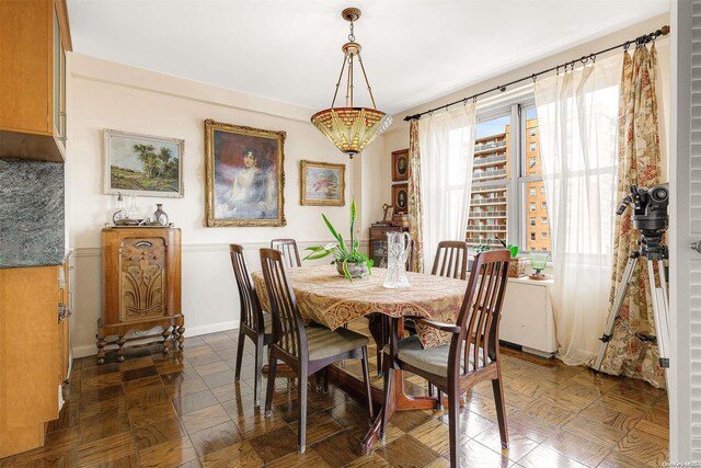 dining space with dark parquet floors and a chandelier