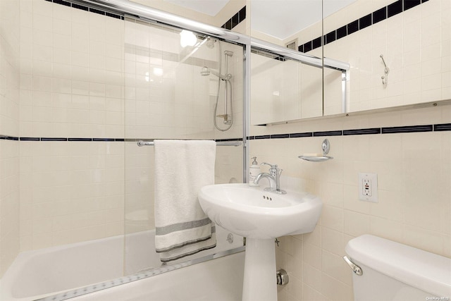 bathroom with shower / bath combination with glass door, toilet, and tile walls