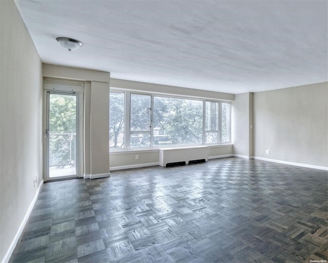 spare room featuring dark parquet flooring and plenty of natural light