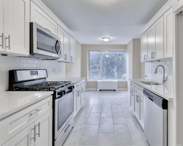 kitchen with appliances with stainless steel finishes, tasteful backsplash, white cabinetry, and sink