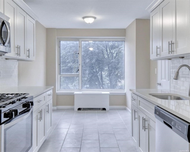 kitchen with backsplash, stainless steel appliances, white cabinetry, and sink