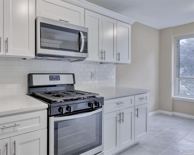 kitchen featuring white cabinets, tasteful backsplash, light tile patterned flooring, light stone counters, and stainless steel appliances