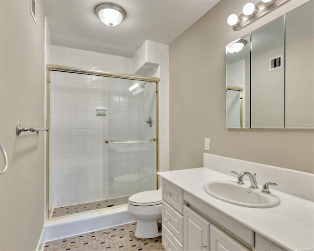 bathroom with tile patterned floors, vanity, an enclosed shower, and toilet