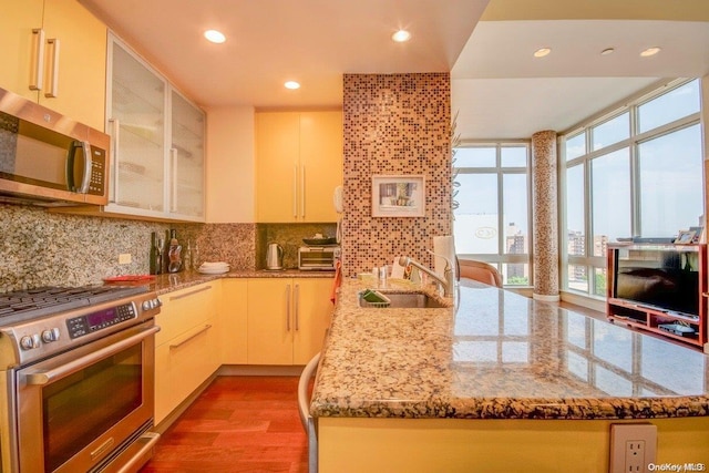 kitchen featuring light stone countertops, sink, light hardwood / wood-style flooring, decorative backsplash, and appliances with stainless steel finishes