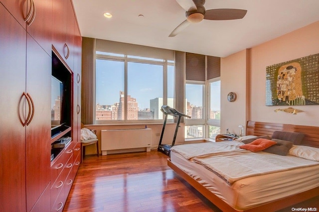 bedroom with ceiling fan, radiator heating unit, and wood-type flooring