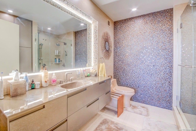 bathroom featuring vanity, tile patterned flooring, toilet, tile walls, and a shower with shower door