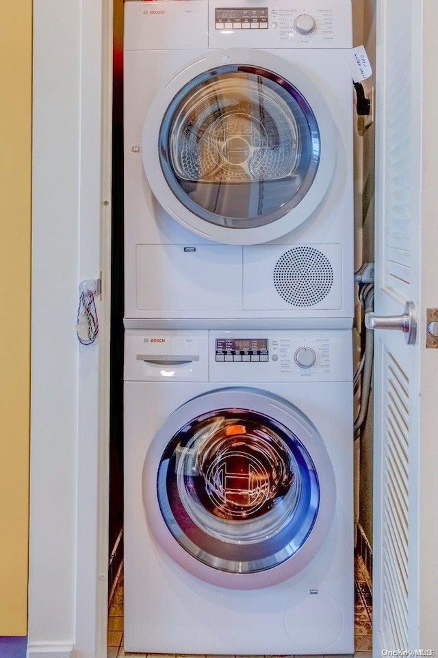 laundry room featuring tile patterned flooring and stacked washing maching and dryer