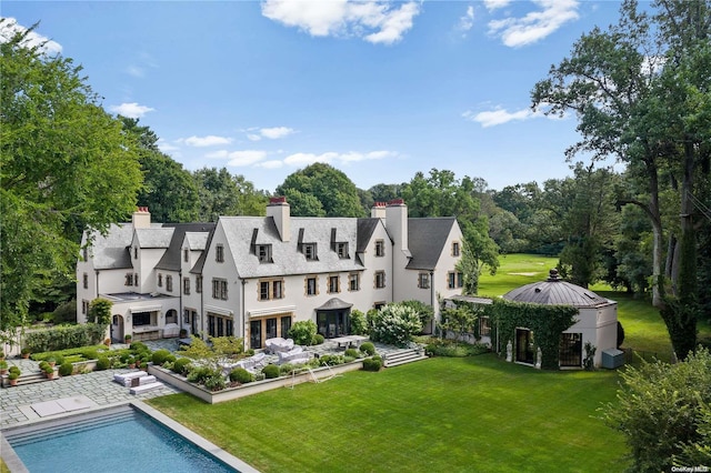 rear view of property featuring a lawn and cooling unit