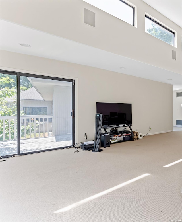 carpeted living room with plenty of natural light and a towering ceiling