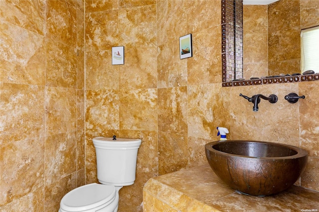 bathroom featuring toilet, sink, and tile walls