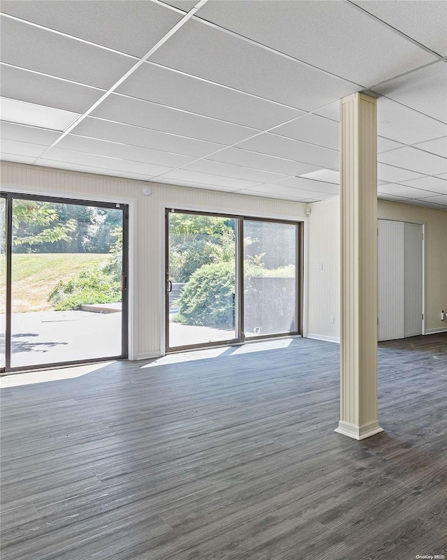 interior space featuring dark hardwood / wood-style flooring, a drop ceiling, and wooden walls