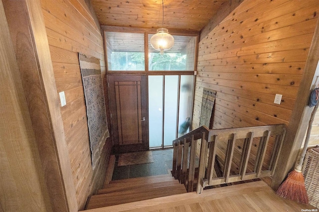 staircase featuring wood-type flooring, lofted ceiling, wooden walls, and wood ceiling