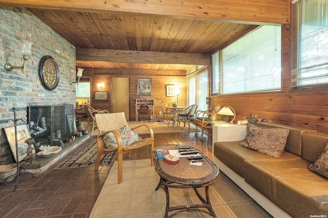 living room featuring beam ceiling, wood walls, wooden ceiling, and a brick fireplace