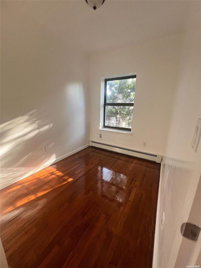 unfurnished room featuring hardwood / wood-style floors and baseboard heating