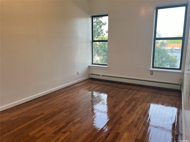 spare room with a baseboard radiator, a wealth of natural light, and dark wood-type flooring