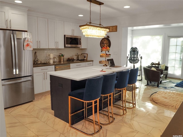 kitchen featuring pendant lighting, white cabinetry, a center island with sink, and stainless steel appliances