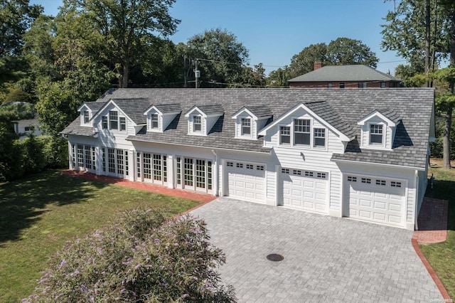 cape cod-style house featuring a front yard and a garage