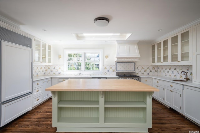 kitchen with white cabinets, custom exhaust hood, a kitchen island, and sink