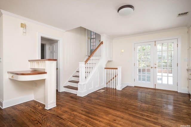 foyer entrance with dark hardwood / wood-style floors, ornamental molding, and french doors