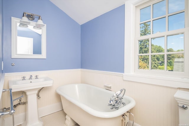 bathroom featuring a tub, tile patterned flooring, and vaulted ceiling