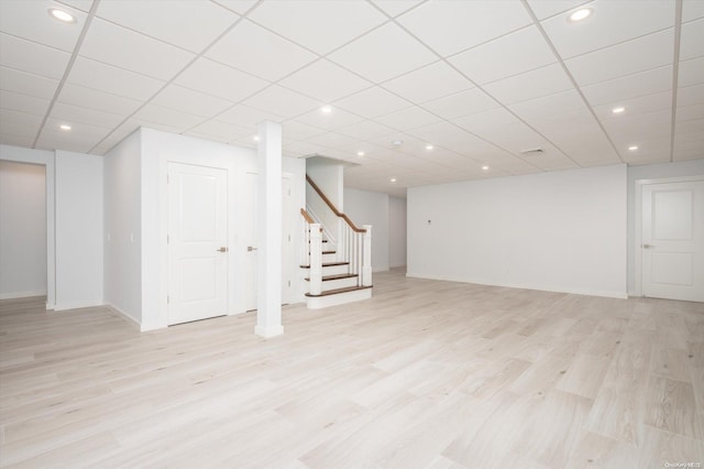 basement featuring light hardwood / wood-style floors and a drop ceiling