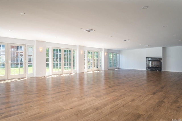 unfurnished living room featuring plenty of natural light, light wood-type flooring, and a premium fireplace