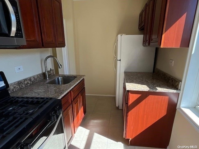 kitchen with light tile patterned flooring, appliances with stainless steel finishes, stone counters, and sink