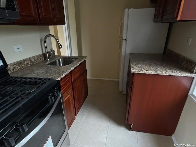 kitchen featuring white refrigerator, sink, light stone countertops, light tile patterned floors, and gas stove