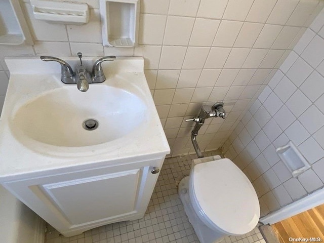 bathroom with tile patterned floors, vanity, tile walls, and toilet