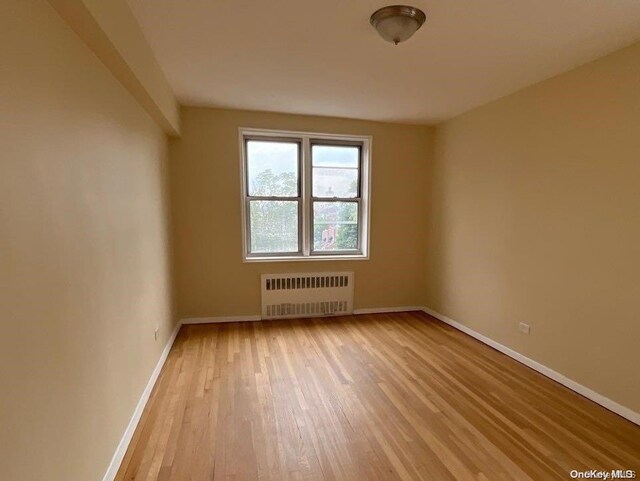 empty room featuring light wood-type flooring and radiator