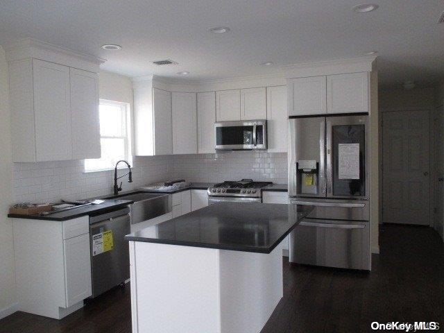 kitchen with a center island, sink, stainless steel appliances, dark hardwood / wood-style floors, and white cabinets