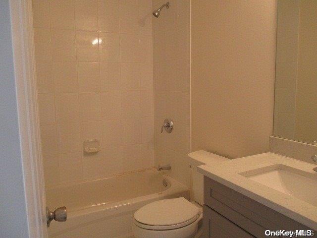 full bathroom featuring tiled shower / bath combo, toilet, and vanity