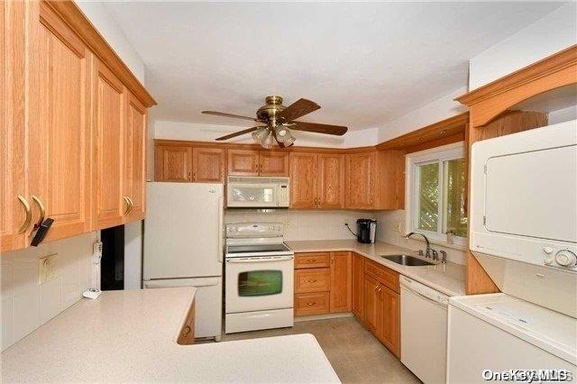 kitchen with ceiling fan, sink, backsplash, stacked washer / dryer, and white appliances