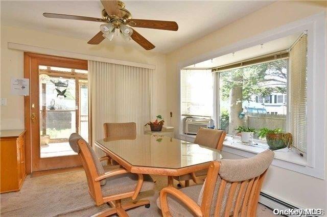 carpeted dining area featuring baseboard heating, ceiling fan, and cooling unit