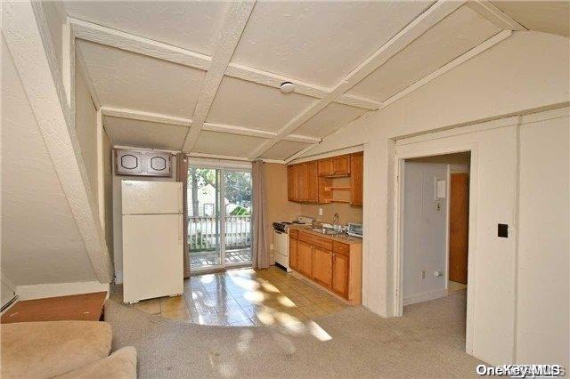 kitchen featuring vaulted ceiling with beams, coffered ceiling, light tile patterned flooring, and white appliances