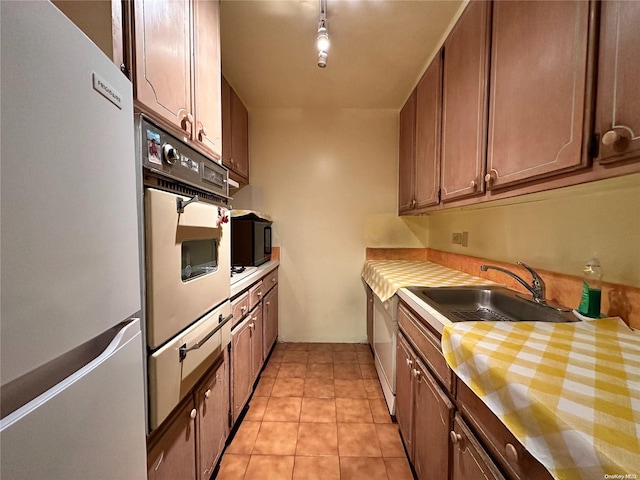 kitchen featuring black appliances, light tile patterned flooring, sink, and track lighting