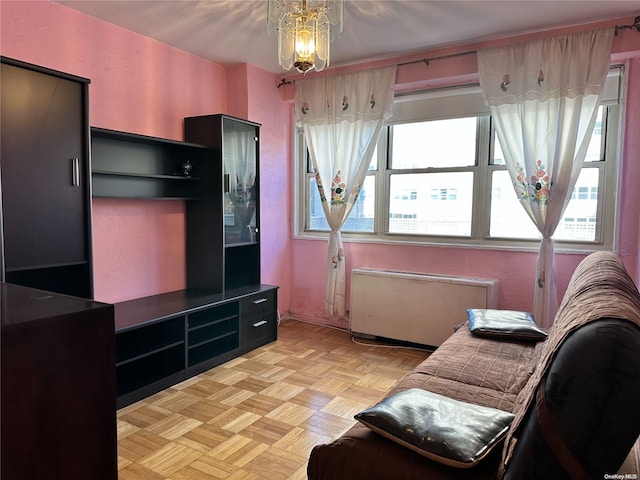 living room featuring a notable chandelier, radiator, and light parquet floors