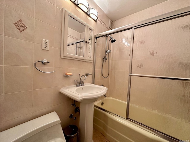 bathroom with shower / bath combination with glass door, backsplash, toilet, and tile walls