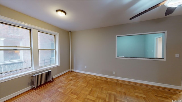 spare room with ceiling fan, radiator heating unit, and light parquet floors