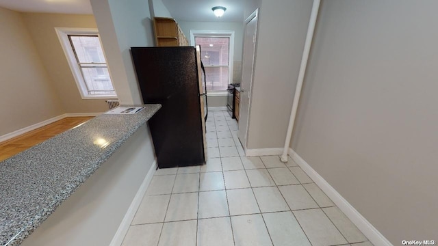 kitchen featuring stone counters, light tile patterned floors, and black appliances