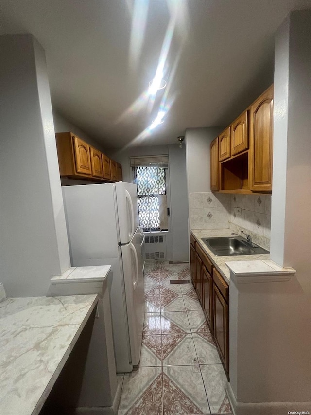 kitchen featuring white fridge, light tile patterned flooring, sink, and tasteful backsplash