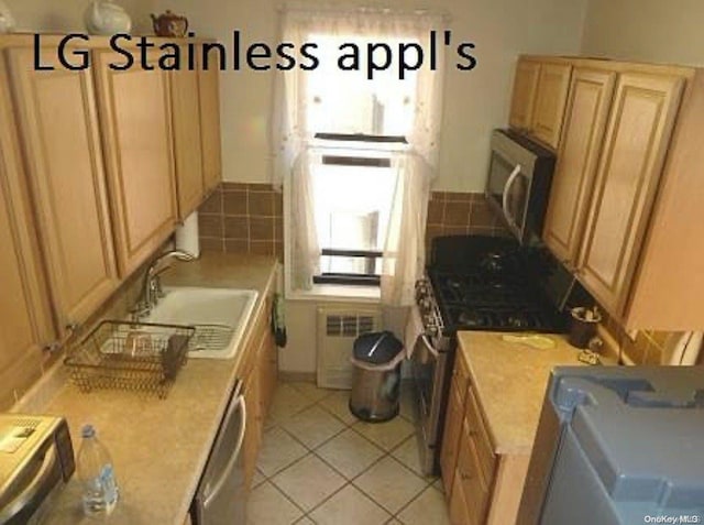 kitchen with radiator, sink, light tile patterned floors, and stainless steel appliances