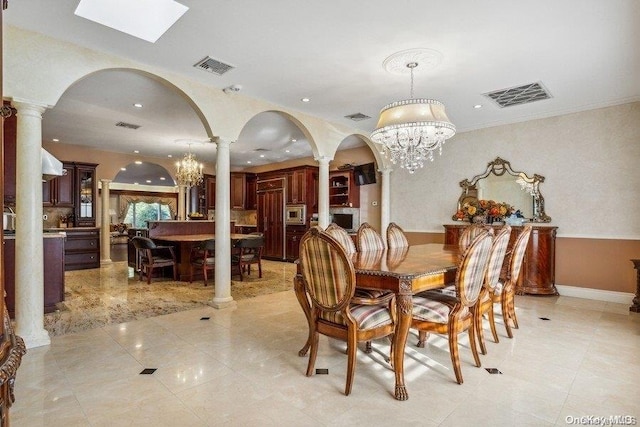 dining room with decorative columns and a chandelier