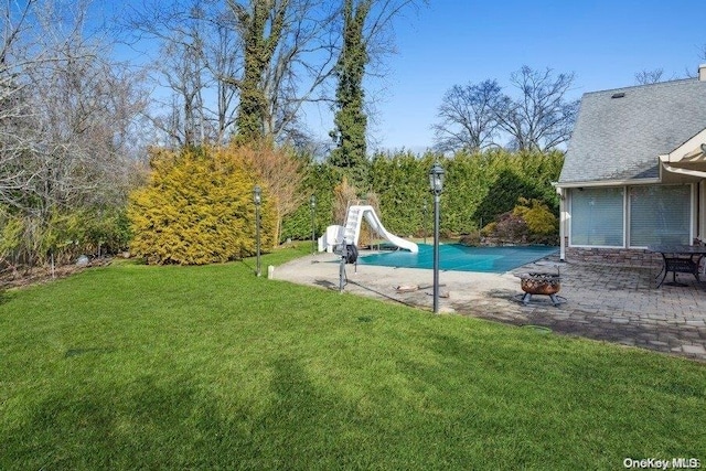 view of swimming pool with a lawn, an outdoor fire pit, a patio, and a water slide